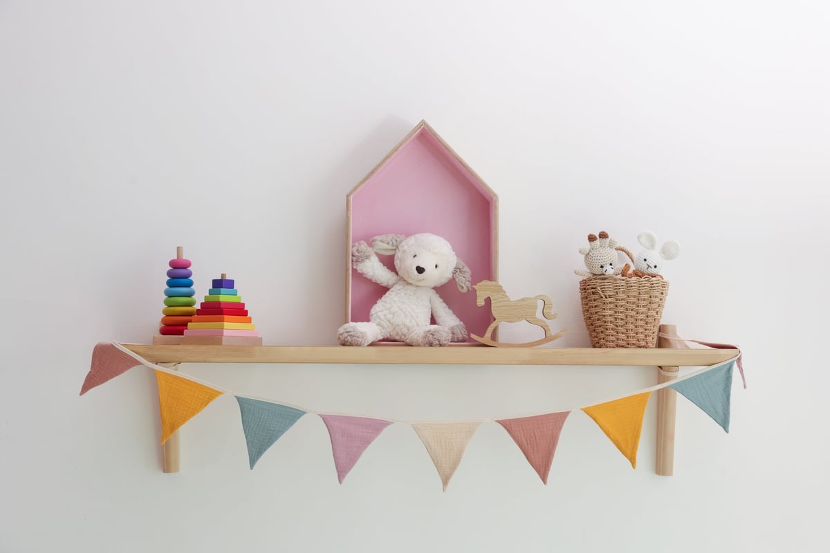 A shelf filled with different toys against a light playroom wall