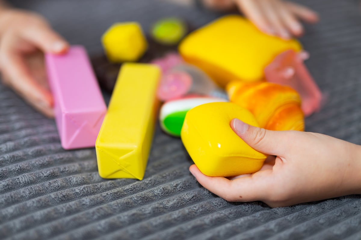 Children's hands holding colourful squishy sensory toys and foam food